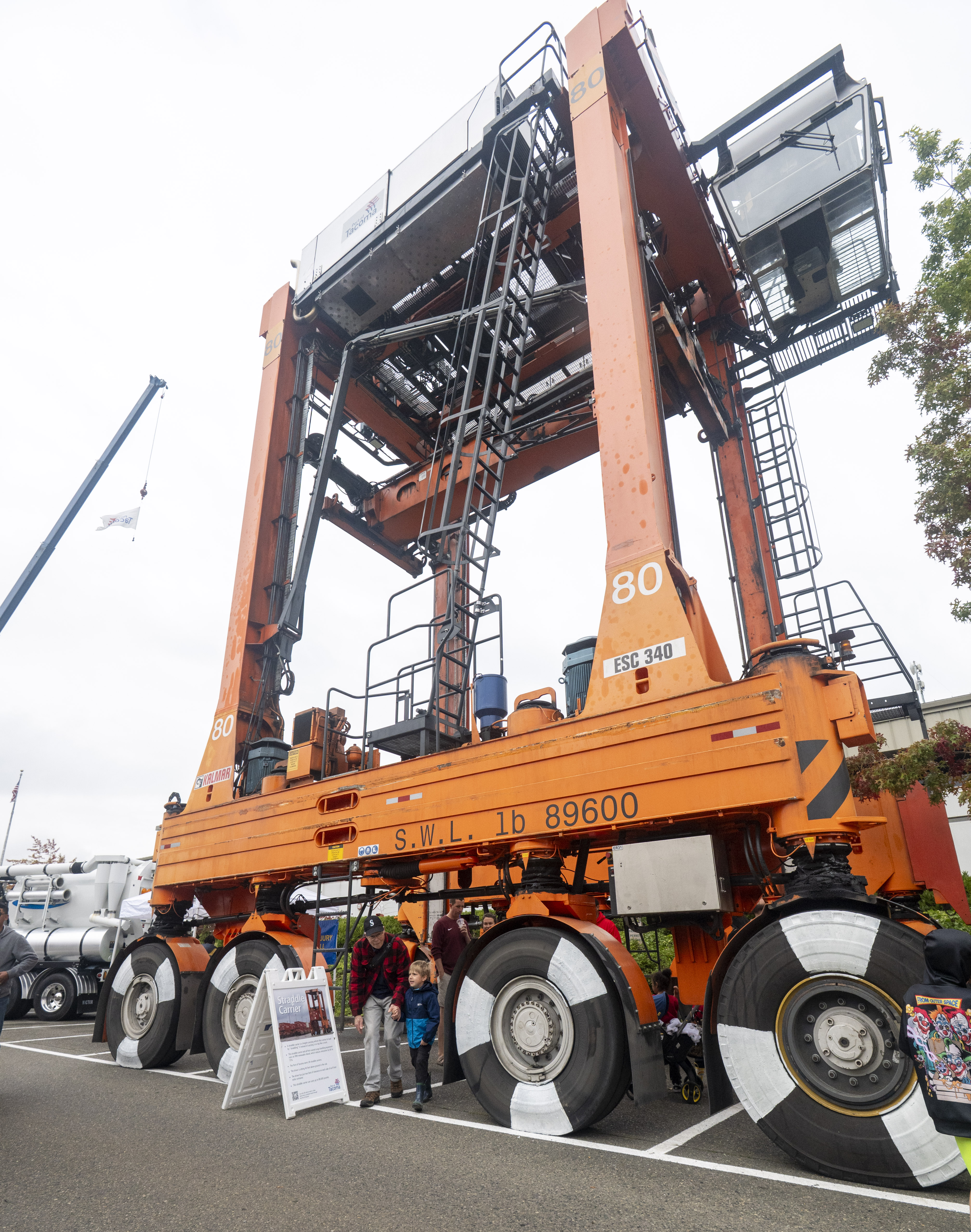 A shot of an orange crane and people standing in front of it.
